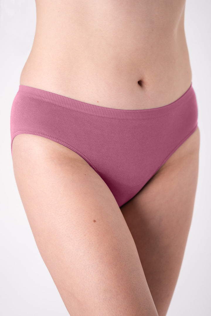 A woman wearing a pair of pink mid-rise underwear on a white background