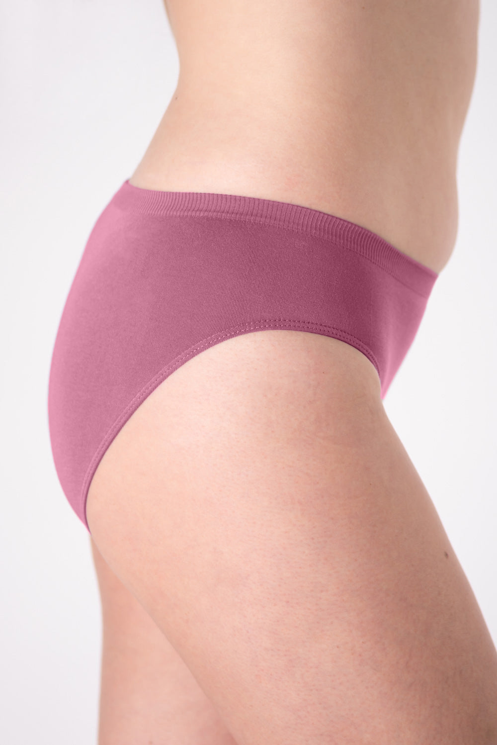 A woman wearing a pair of pink mid-rise underwear on a white background